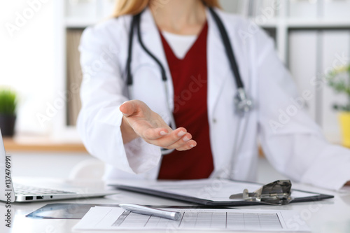 Female medicine doctor offering helping hand in office closeup. Physician ready to examine and save patient. Friendly and cheerful gesture. Medical cure and tests advertisement concept