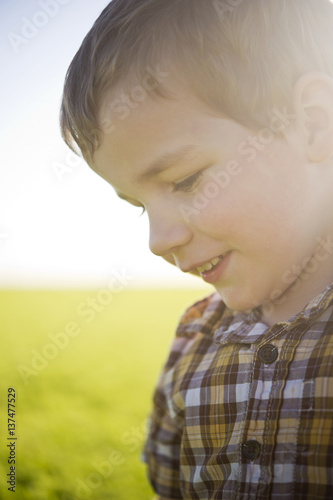 Young boy's profile with sunlight hitting his face in a farm field; Saskatchewan, Canada photo