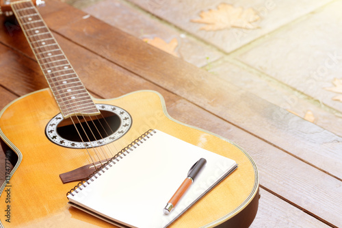 Photos acoustic guitar with notebook and pen on wood background