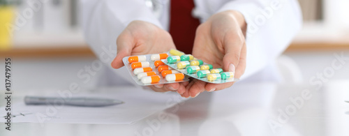 Female doctor hand holding pack of different tablet blisters at workplace closeup. Panacea, life save service, prescribe medicament concept photo