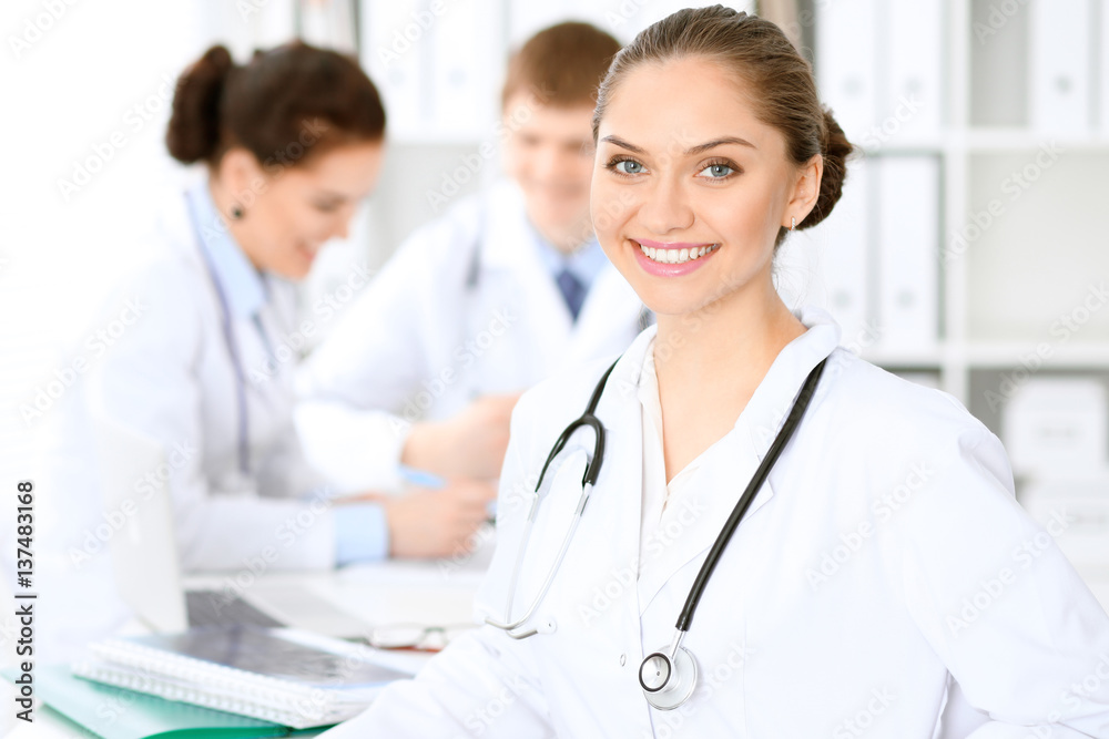 Happy doctor woman with medical staff at the hospital sitting at the table and discussing medical history Happy doctor woman with medical staff at the hospital sitting at the table and discussing medical history