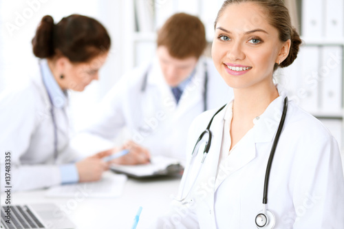 Wallpaper Mural Happy female doctor with medical staff while sitting at the table.  Successful team at health care and medicine concept Torontodigital.ca
