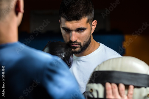 Portrait of young man practicing kickboxing with his coach