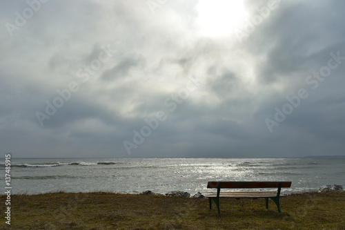 Old wooden bench by the sea in a dark winter day