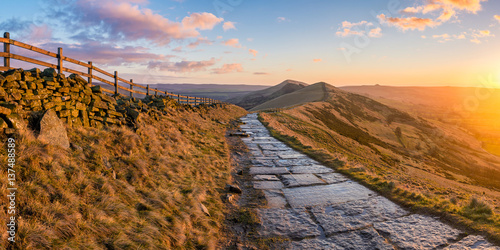 Beautiful vibrant sunrise at Mam Tor in the Peak District with a stone footpath.