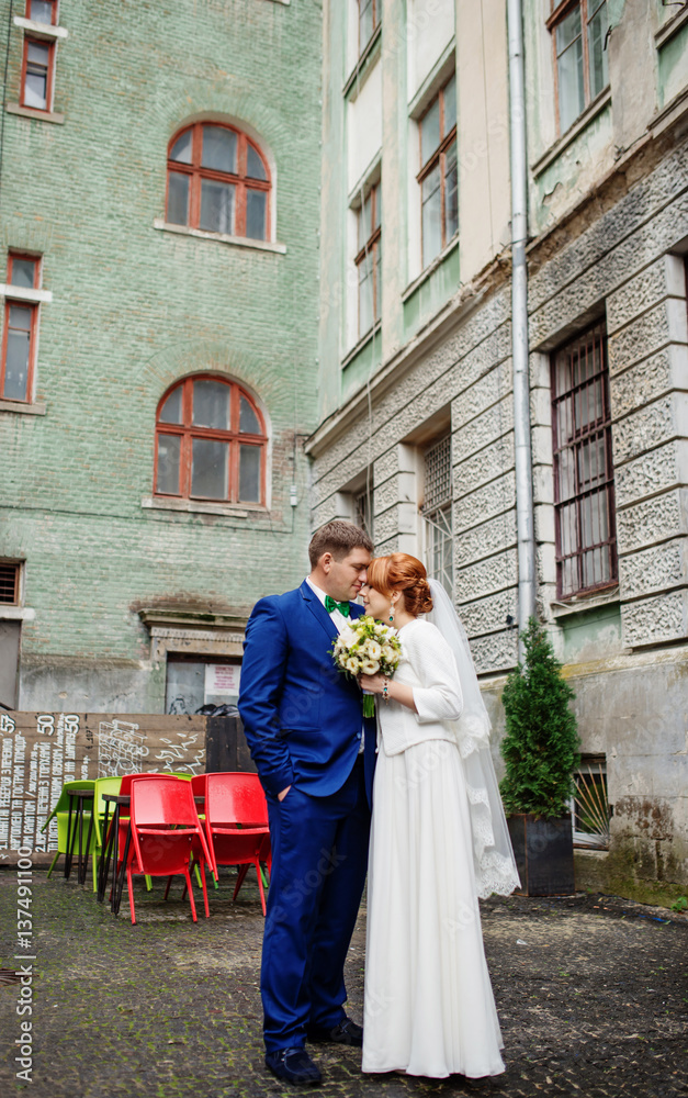 Wedding couple in love at yard of old street town background coloured chairs.