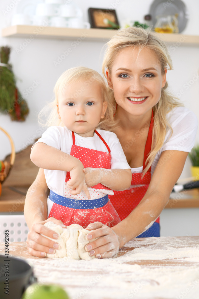 Happy family in the kitchen. Mother and child daughter cooking holiday pie or cookies for Mothers day, casual lifestyle photo series in real life interior Happy family in the kitchen. Mother and child daughter cooking holiday pie or cookies for Mothers day, casual lifestyle photo series in real life interior
