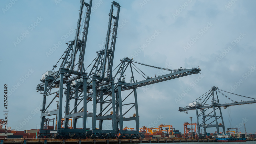 Large dockside gantry steel crane lifting a containers at the port of Laem Chabang in Chonburi Province, Thailand in vintage style image.