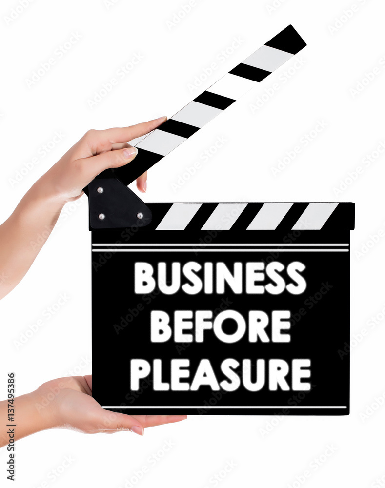 Hands holding a clapper board with BUSINESS BEFORE PLEASURE text