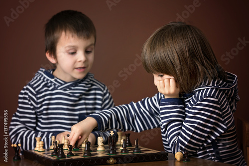 Little boys, playing chess. Smart kid, isolated, playing chess agains his brother