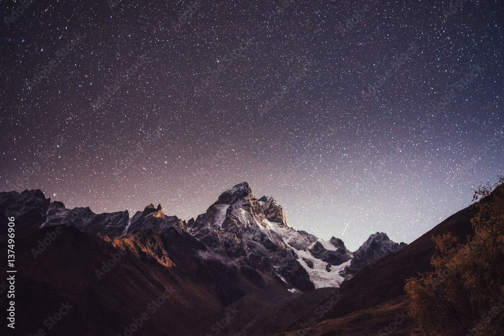 Naklejka premium Fantastic starry sky. Autumn landscape and snow-capped peaks