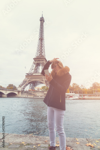 Cute girl using cellphone with Eiffel tower in the background, Paris - France. © astrosystem