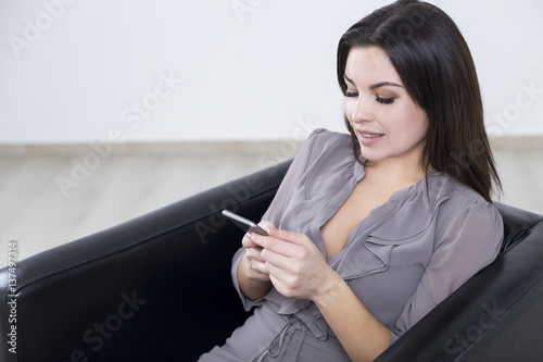 Close up of girl in gray in armchair with phone