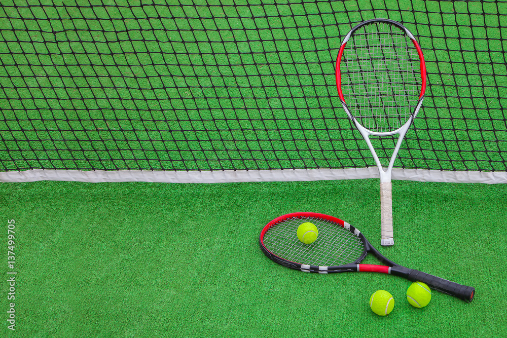 tennis racket with balls on green grass