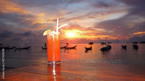 punch cocktail in flash light at shore during sunset time - sihouettes with flash light , soft and select focus 