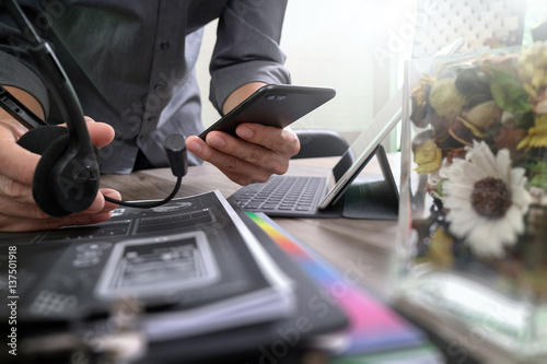 Man using VOIP headset with digital tablet computer docking keyboard,smart phone,concept communication, it support, call center and customer service help desk,vase flowers on wooden table