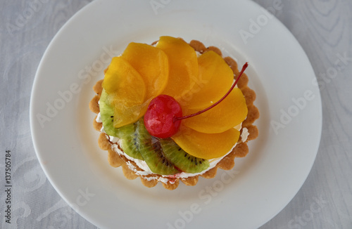 Tartlets with cream and fruit. Cherry, peach and kiwi.