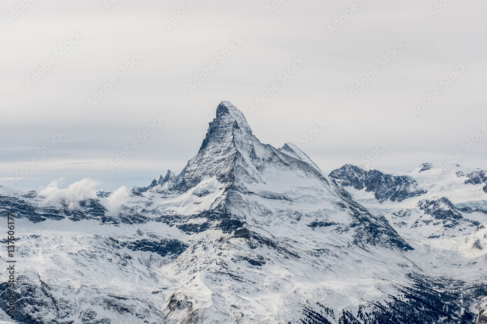 Fototapeta premium Scenic moody view on snowy Matterhorn peak with sky and clouds in background, Switzerland.