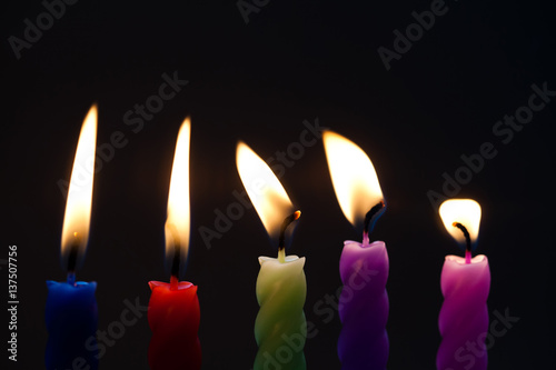 Macro view candle flames. Selective focus. Shallow depth of field colored candles on black background. Light and darkness concept photo