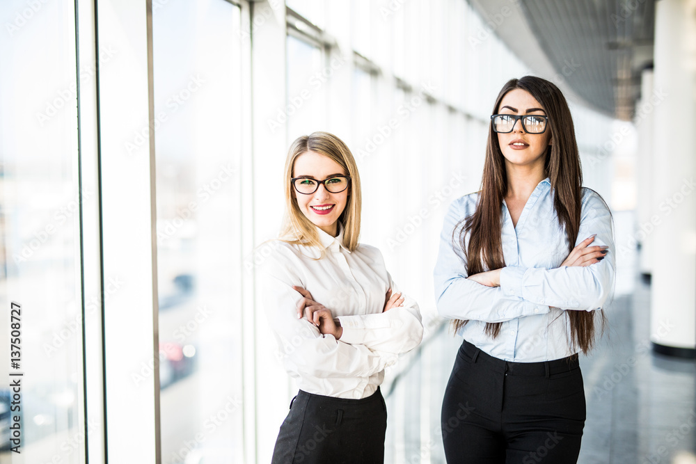 Obraz premium Young business ladies in office hall over panoramic windows.