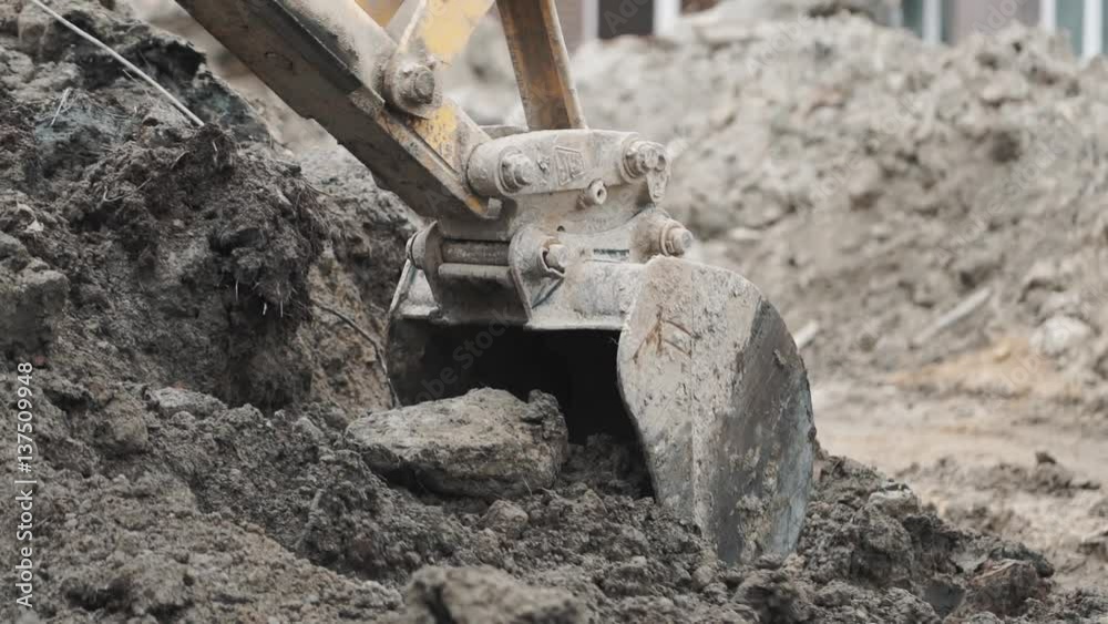 Excavator laddle digging soil sand and dirt pile at building site. Slowmotion, close up Excavator laddle digging soil sand and dirt pile at building site. Slowmotion, close up