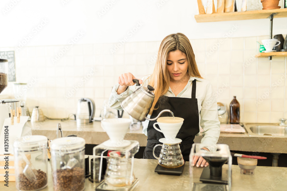 Pretty female barista brewing coffee