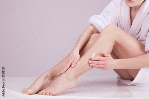 Jeune femme appliquant une crème sur ses jambes photo