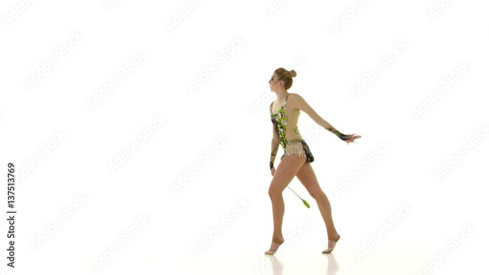 Rhythmic gymnast throws mace up and catches her. White background