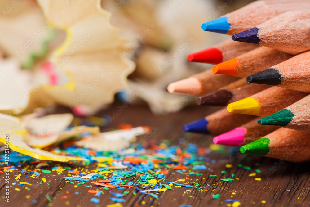 Wooden colorful pencils with sharpening shavings, on wooden table Wooden colorful pencils with sharpening shavings, on wooden table