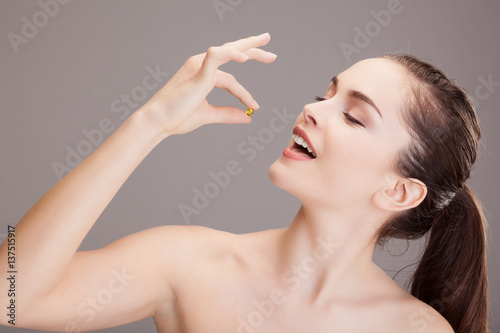 Portrait d'une jeune femme s'apprêtant à prendre une gélule d'oligo éléments 