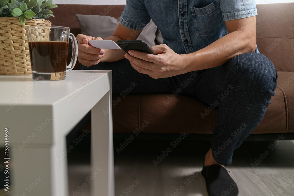 hipster hand using smart phone,digital tablet docking keyboard,holding cradit card payments online business,sitting on sofa in living room,work at home concept hipster hand using smart phone,digital tablet docking keyboard,holding cradit card payments online business,sitting on sofa in living room,work at home concept