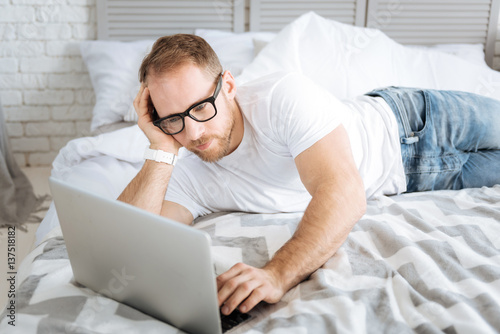 Pleasant bearded man using laptop at home