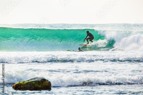 Surfing and turquoise wave in ocean. Sunny day