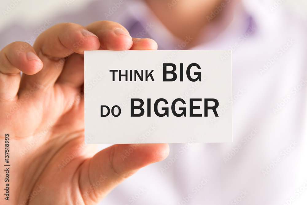 Businessman holding THINK BIG DO BIGGER text card
