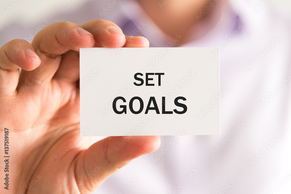 Businessman holding a card with text SET GOALS