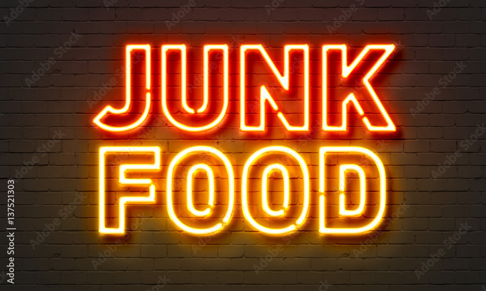 Junk food neon sign on brick wall background.