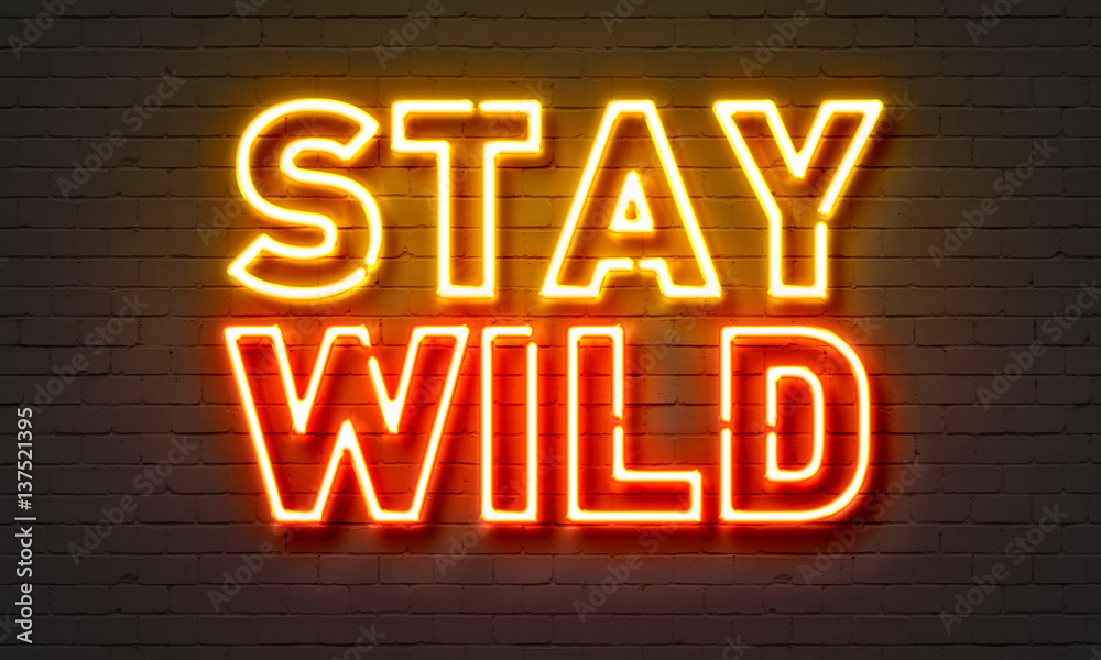 Stay wild neon sign on brick wall background.