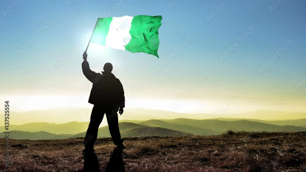 silhouette man waving Nigeria flag 