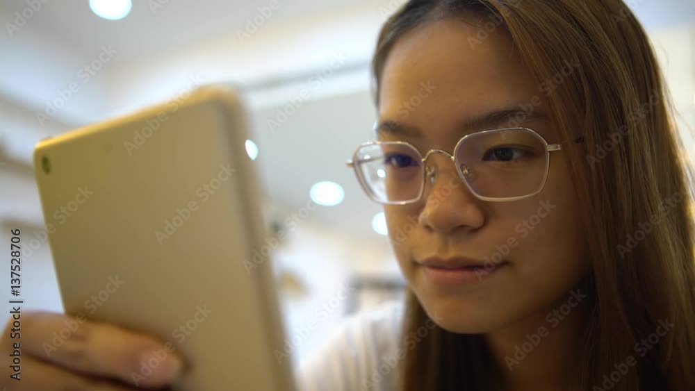 4K Asian Woman is smiling happiness when using tablet touch screen to chat and contact people on the distance in a coffeeshop. Girl checks social network with modern wireless technology in asia-Dan 4K Asian Woman is smiling happiness when using tablet touch screen to chat and contact people on the distance in a coffeeshop. Girl checks social network with modern wireless technology in asia-Dan