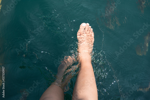 Dipping feet in water off a dock on a hot summer day.