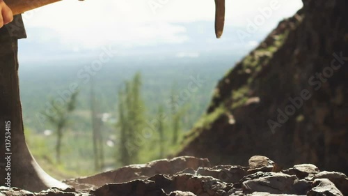 A miner is mining ore with a pickaxe in the mountains