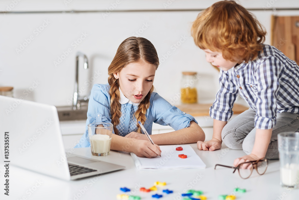 Smart diligent girl explaining her brother basic calculations Smart diligent girl explaining her brother basic calculations