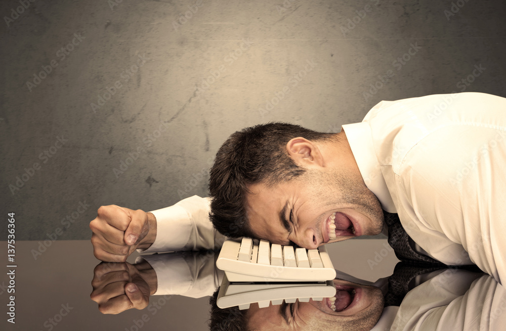 Obraz premium Frustrated businessman's head on keyboard
