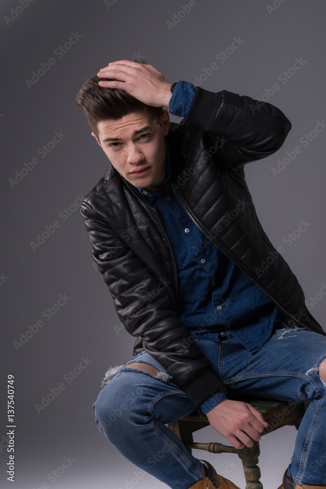 Casual young man in black jacket, jeans and boots on black background. Studio shoot. Casual young man in black jacket, jeans and boots on black background. Studio shoot.