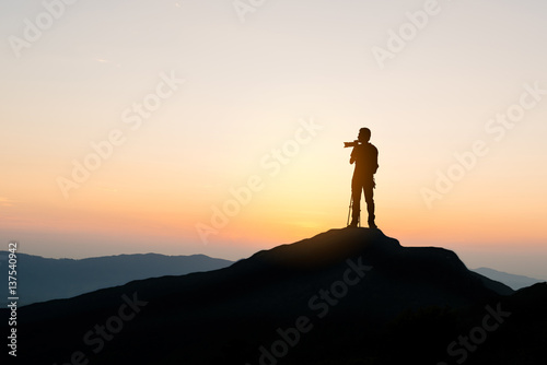 photographer on top of mountain at sunset background