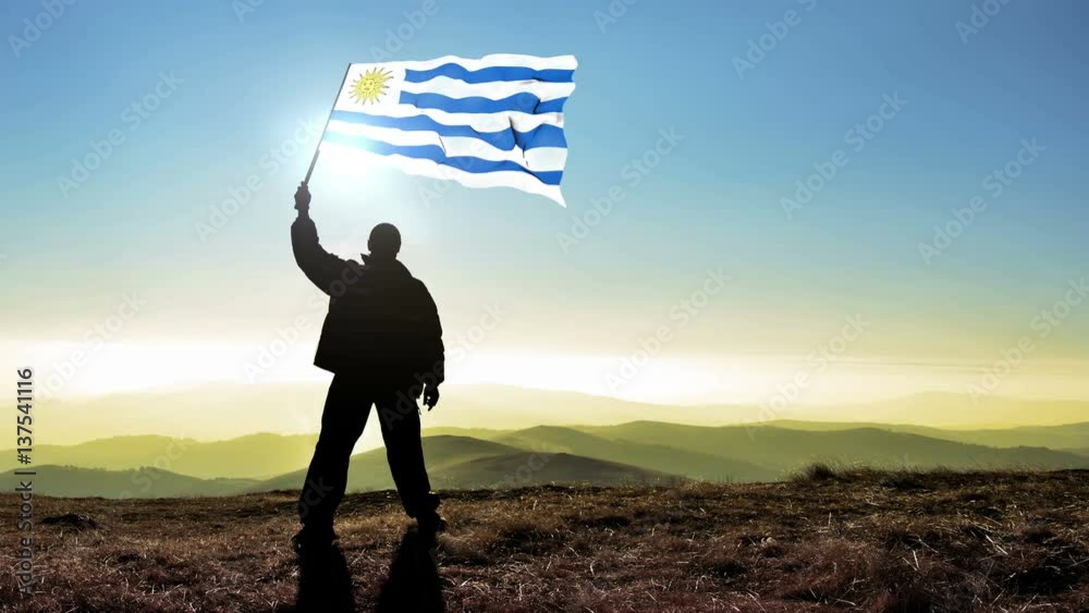 silhouette man waving uruguay flag 