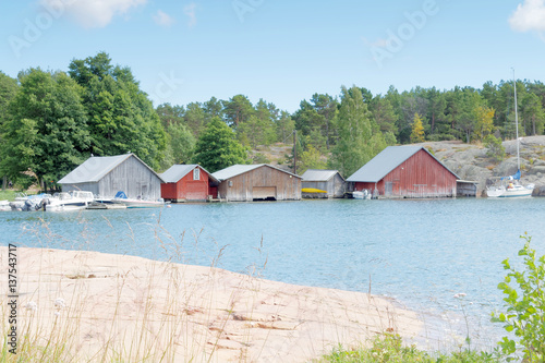 Red and gray boathouses, rock and trees photo