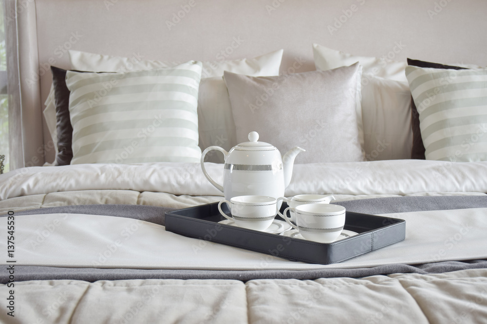 Decorative tray of tea set on the bed in modern bedroom interior Decorative tray of tea set on the bed in modern bedroom interior