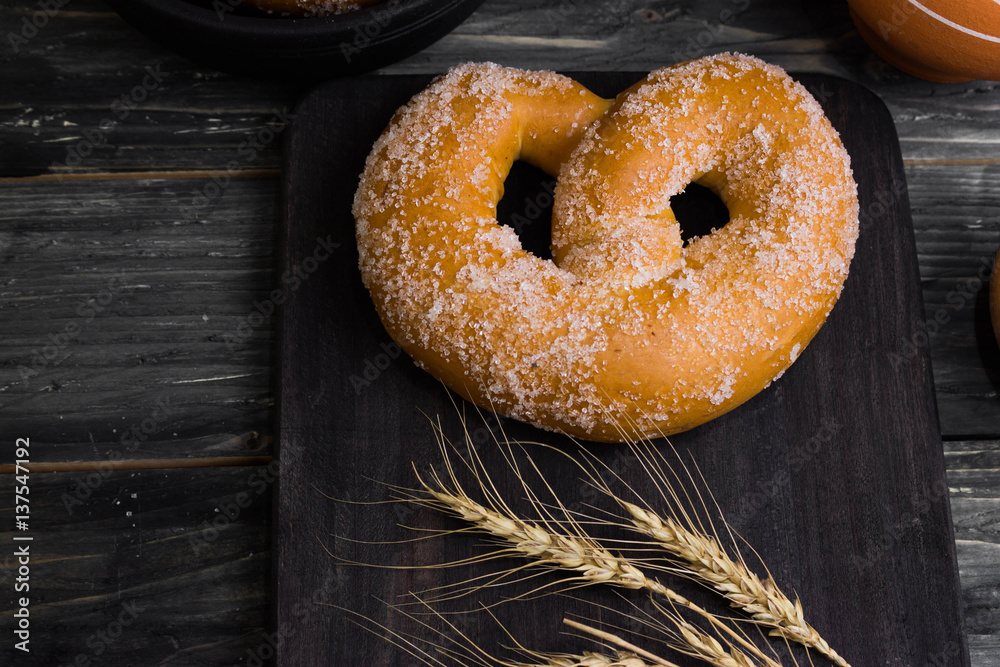 Pretzel in sugar on a wooden background in rustic style. Tasty dessert.