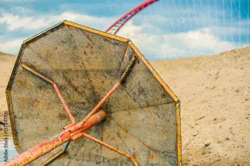abandoned rusty metal parasol on the sandy beach, on a background of red bridge and blue sky